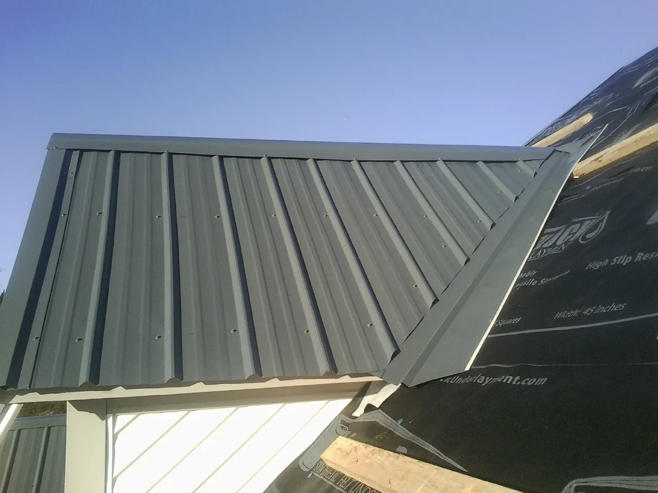 Gray metal roof panels going on over a garage gable in Mission