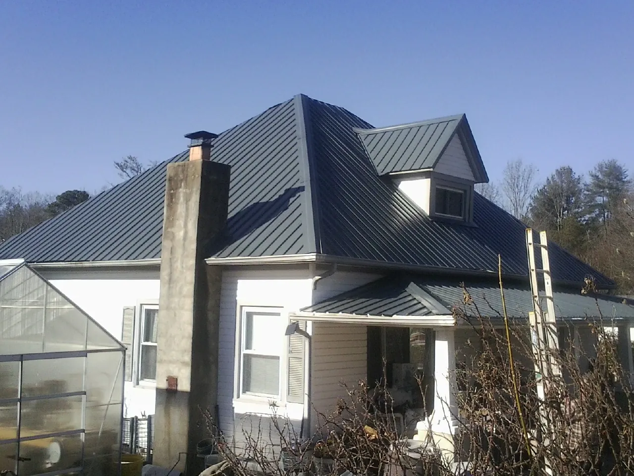 Dark blue standing seam metal roof on a white farmhouse with dormer — Slate & Tile Roof Repair by Roofing Brothers in Mission