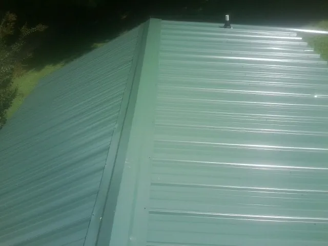 New green metal panels meeting at the ridge of a roof — Flat Roof Repair work by our crew in Mission