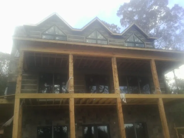 Dormers and porch framing on a large log home under construction — Roof Coating work by our crew in Mission