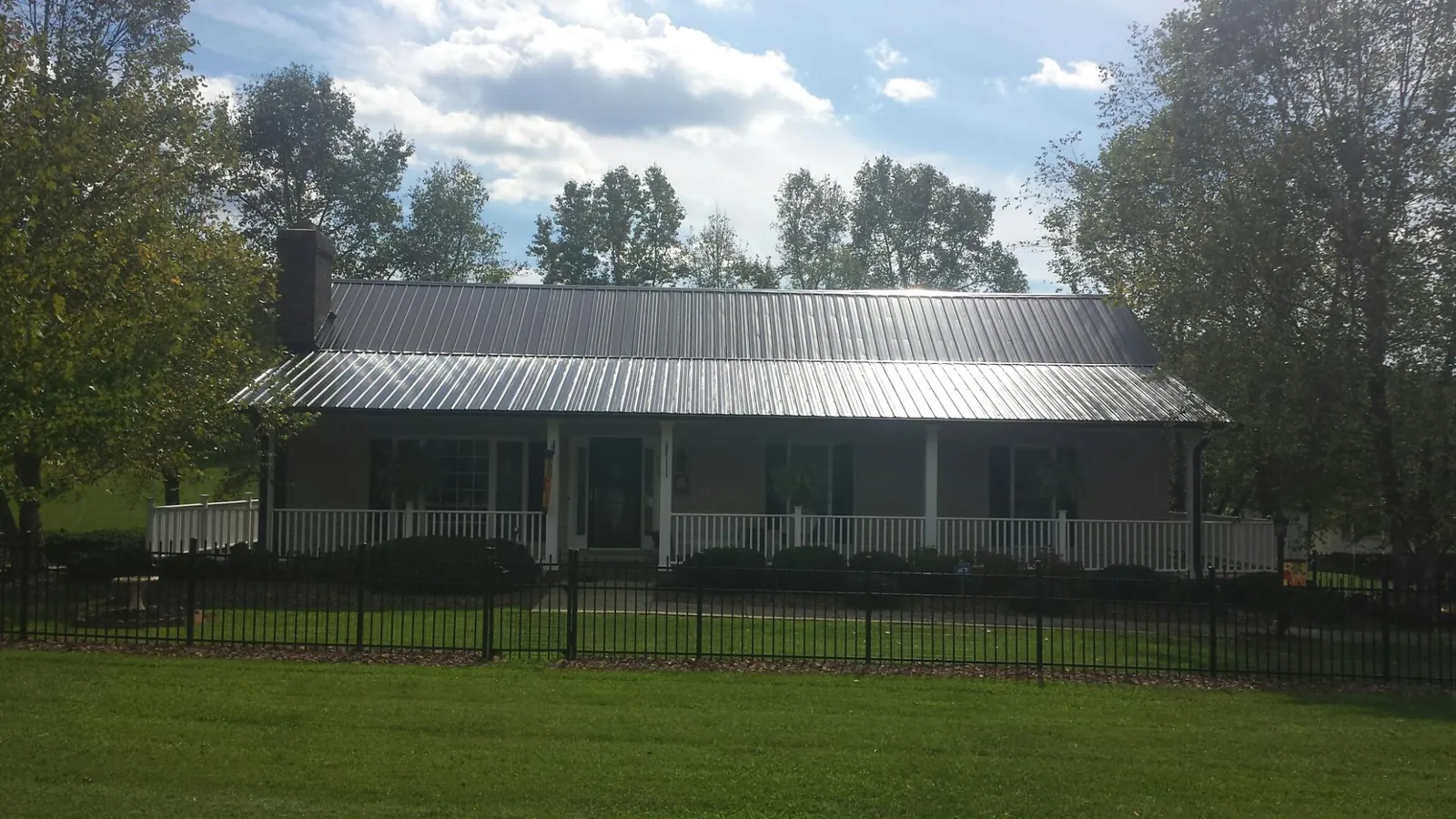 Gray metal roof on a brick ranch with a full width front porch — Gutter Guard Installation work by our crew in Mission